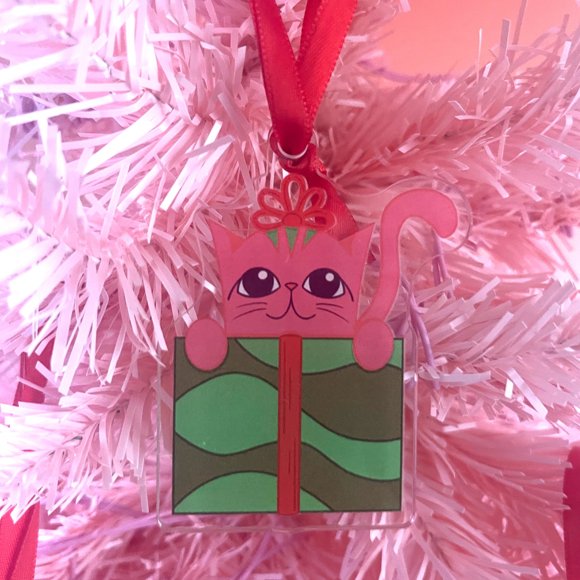 Pink cat-shaped gift box on a pink tinsel background