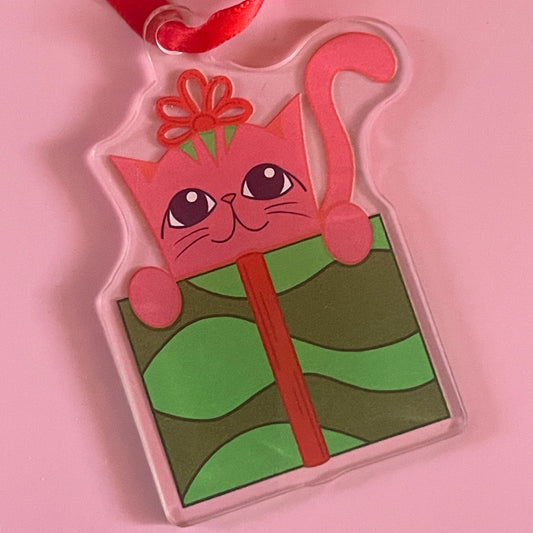 Pink cat-shaped gift box with a red bow on a pink background