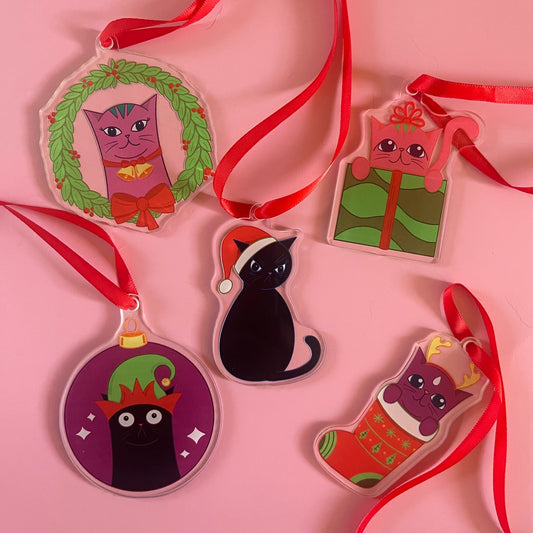 Set of Christmas-themed cat ornaments on a pink background